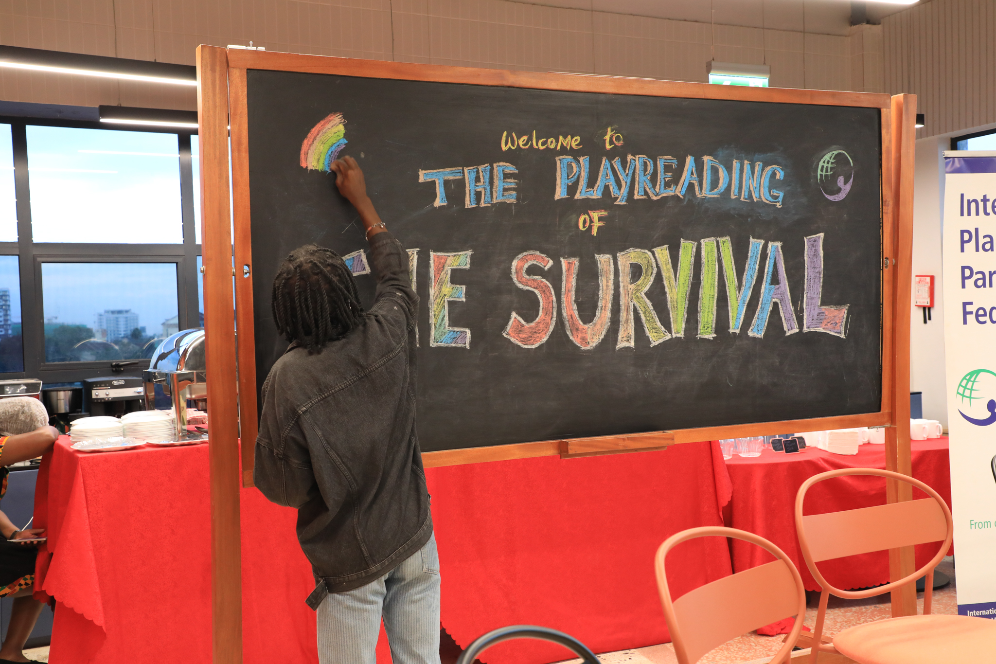 A participant writes The Survival on the blackboard at the play reading event.