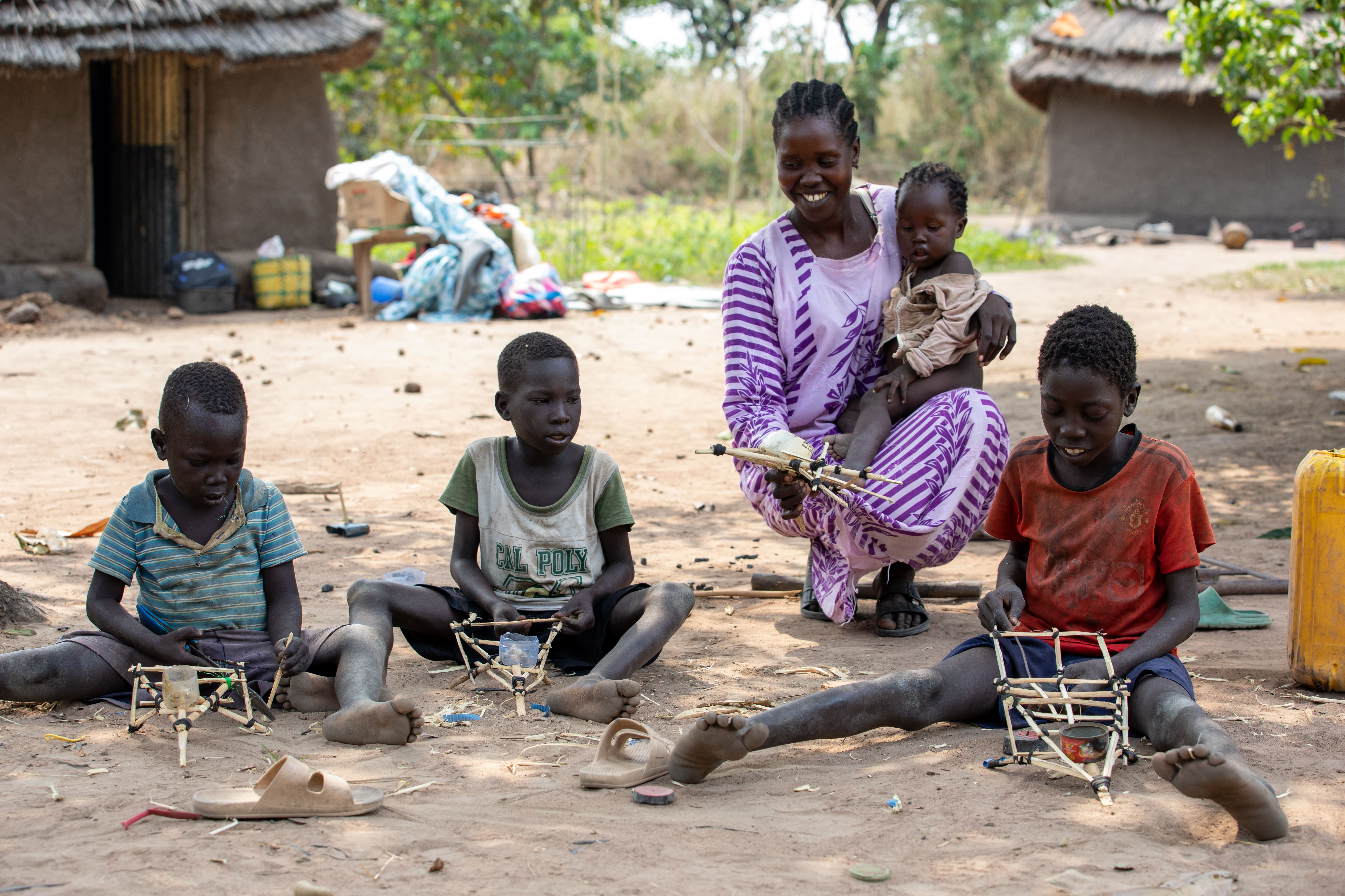 Rose Nyoka is showing her last born the makeshift of a vehicle made by the children in Rokon IDP Camp – RHASS South Sudan